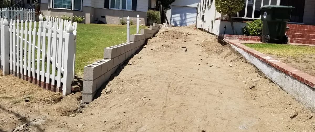 Concrete block wall going up beside the excavated driveway, T&N Remodeling