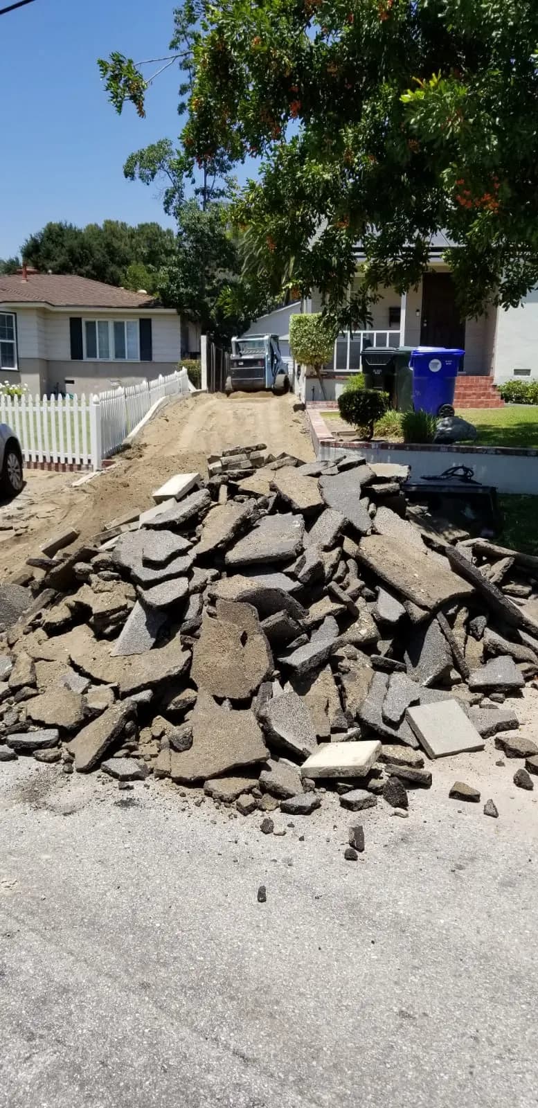 Broken-out asphalt piled at the curb during demolition by T&N Remodeling